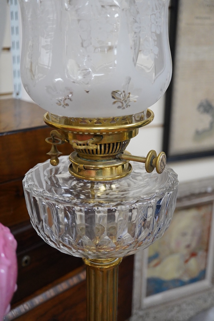 Three Victorian brass column oil lamps, with original brass fittings, glass reservoirs and shades. Tallest 72cm high.